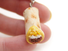Load image into Gallery viewer, Miniature tortilla with filling held between fingers on a white background